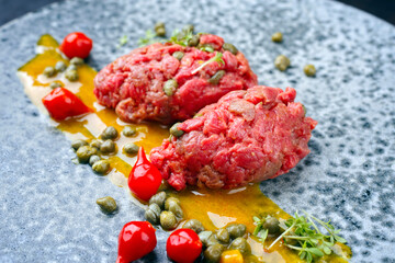 Modern Style rohes Gourmet Tartar vom Rinderfilet mit Senf Sauce und Kapern serviert als close-up...