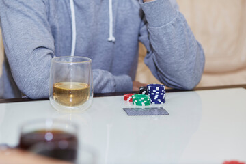 Concept of playing poker on the table with chips and cards. A glass of whiskey. Gambling concept. Copy space. Selective focus.