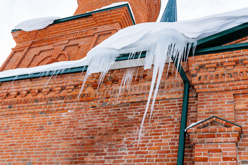 Sharp icicles on the roof of the building.Dangerous.Removal of icicles from the facade. Frozen...