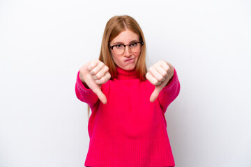 Young redhead woman isolated on white background showing thumb down with two hands