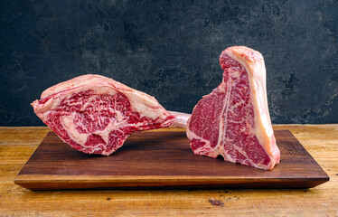 Two raw dry aged wagyu porterhouse and tomahawk beef steaks offered as close-up on modern design...