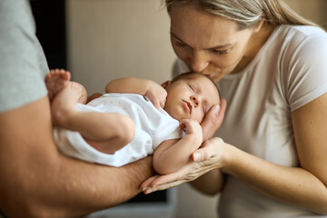 Portrait of happy young father hugging and kissing his adorable newborn child.