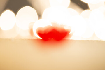 Valentine's Day greetings concept. Little red wooden heart close up, party lights bokeh on...