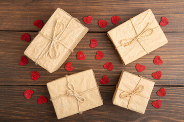 Valentine's Day greetings concept. Little red wooden crafted hearts and gift boxes on the wooden background. Valentines greeting card.