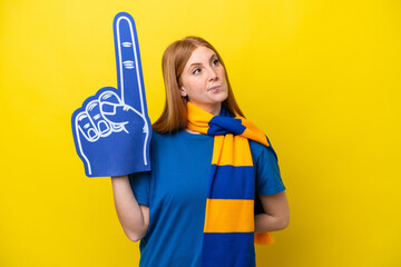 Young redhead sports fan woman isolated on yellow background and looking up