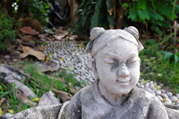 Small stone statue of a girl in a temple of Bangkok in Thailand