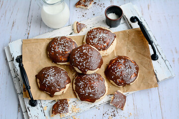 Homemade vanilla meringue with chocolate icing on a wooden tray. Top view