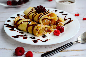 Closeup of a plate with pancakes and berries on a light wooden background. The concept of a delicious and nutritious breakfast