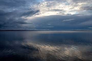 dark blue cloudy evening sky with reflection in lake water