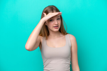 Teenager Russian girl isolated on blue background looking far away with hand to look something
