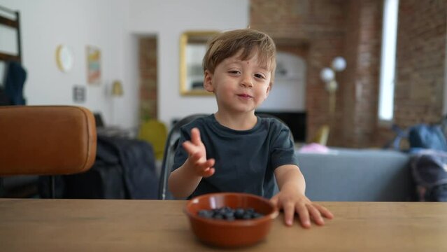 Child hands grabbing blueberry from bowl healthy blueberries