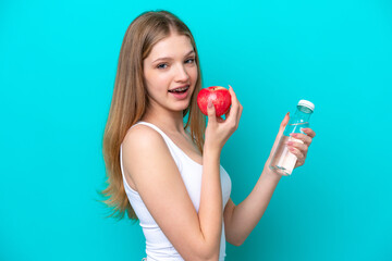 Teenager Russian girl isolated on blue background with an apple and with a bottle of water