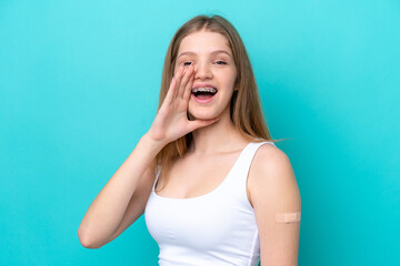 Teenager Russian girl wearing a band aids isolated on blue background shouting with mouth wide open