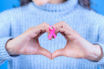Adult woman holding the Pink Ribbon to support people living with breast cancer.