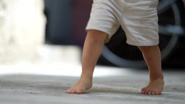 Child kicking ball barefoot outside