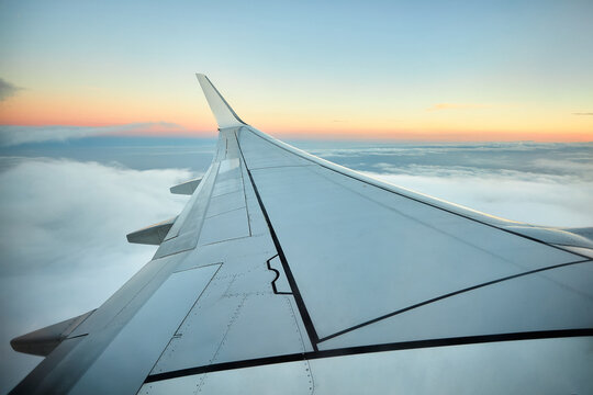 View from an airplane. Wing of passenger plane at sunset with cloudy sky. Concept, travel in times of covid