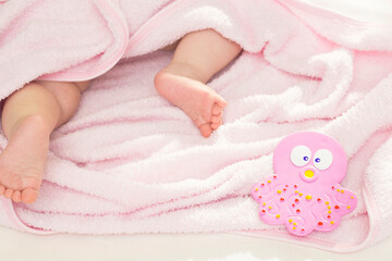 Obraz na płótnie Canvas A cute baby is lying in a pink towel after a bath. Bathing babies, newborns.