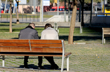 Couple talking sitting on a bench in the city