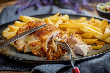 Fried chicken breast stuffed with bacon and cheese served with chips and salad. - obrazy, fototapety, plakaty