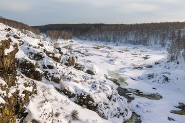 Winter landscape with trees and sky from the high rocky river bank