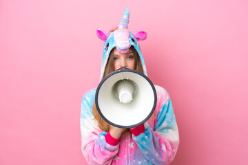 Teenager Russian girl with unicorn pajamas isolated on pink background shouting through a megaphone