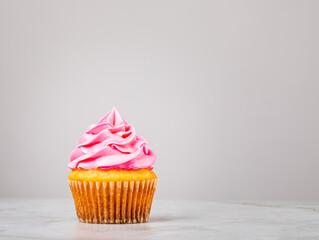 Vanilla Cupcake with pink Buttercream Icing on grey.