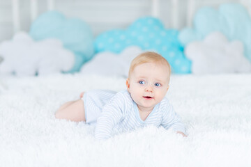 baby on the bed in blue pajamas goes to bed or wakes up in the morning, baby boy blonde six months