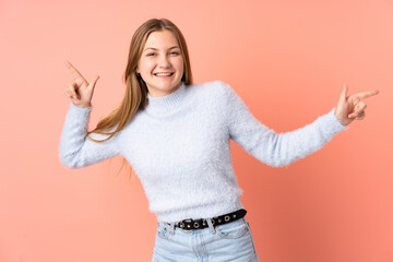 Teenager Ukrainian girl isolated on pink background pointing finger to the laterals and happy