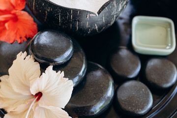 abstract background close up of black balance zen stones and hibiscus flowers in spa area of luxury hotel in Maldives