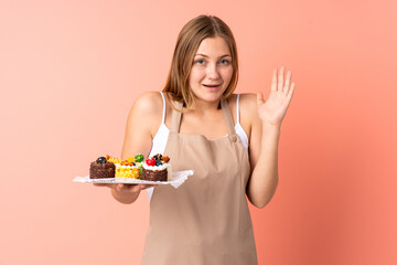 Pastry Ukrainian chef holding a muffins isolated on pink background with surprise facial expression
