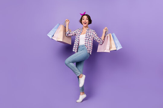 Photo of adorable impressed woman wear plaid shirt rising shoppers isolated violet color background