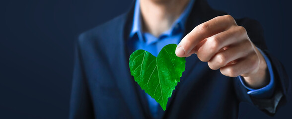 Businessman holding a green heart leaf  Business with corporate social responsibility and environmental concern. Environmental and Ecology Care Concept.. ESG Concept. Nature 