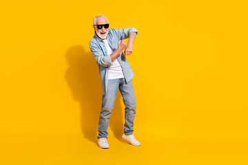 Full length body size view of attractive cheerful carefree grey-haired man having fun isolated on bright yellow color background