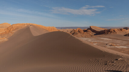 Eine riesige, rote Sanddüne zieht sich durch das Tal des Mondes innerhalb der Atacama Wüste im...