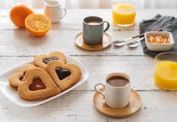 Breakfast concept with coffee, orange juice and cookies in heart shape with jam