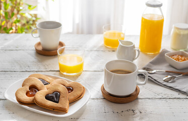 Breakfast concept with coffee, orange juice and cookies in heart shape with jam