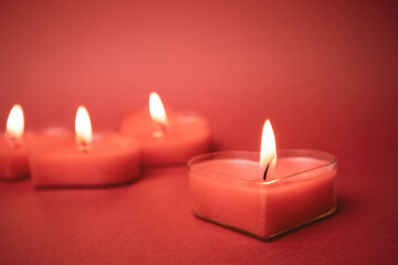 Red burning heart-shaped candles with blazing flames. Tongues of fire on a red background. Valentine's Day, passion, love, feelings, romantic mood concept. Monochrome wallpaper. Decor for February 14.