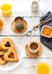 Breakfast concept with coffee, orange juice and cookies in heart shape with jam
