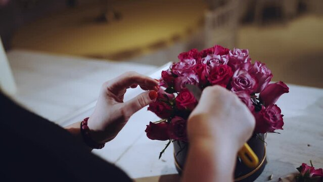 Florist collects a bouquet of roses, a hatbox with flowers of roses
