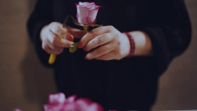 Florist collects a bouquet of roses, a hatbox with flowers of roses
