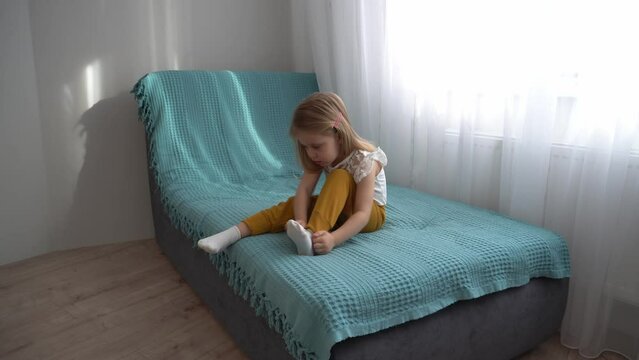 The girl puts on socks while sitting on the sofa. The girl is going for a walk.