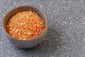 raw dry red and yellow lentils in a ceramic bowl on a grey plastic surface