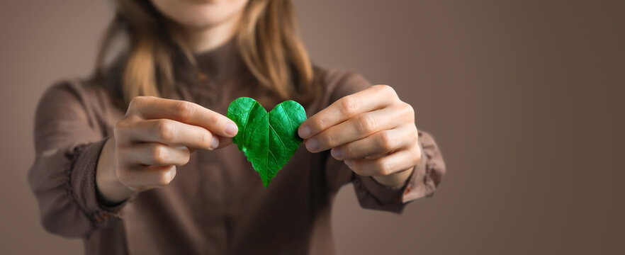 Woman on redshirt hands holding heart-shaped leaves CSR ,ESG, Eco green sustainable living, environmental, social and corporate governance. Environmental and Ecology Care Concept. 