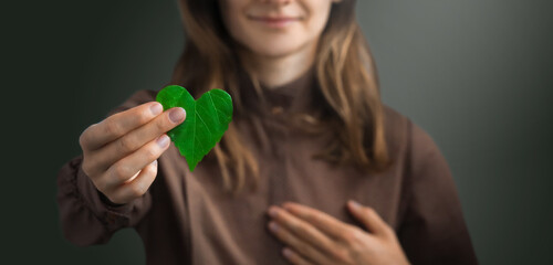 Woman on redshirt hands holding heart-shaped leaves CSR , ESG, Eco green sustainable living, environmental, social and corporate governance. Environmental and Ecology Care Concept.