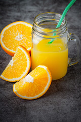 Naklejka na ściany i meble A glass of orange juice on a dark background