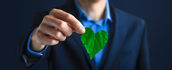 Businessman holding a green heart leaf. Company corporate social responsibility and environmental...
