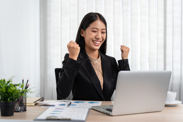 Business woman is working about new business project on laptop and raised your hands when finished work