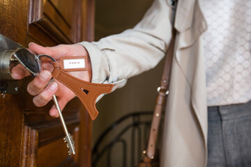 Obraz premium Hand opening a wood door with keys and Eiffel tower key ring