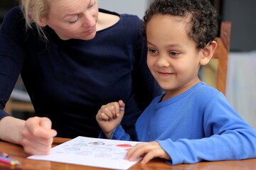 child doing homework learning at home with mother sitting at a table stock photo	