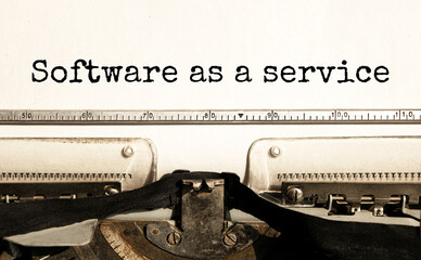 The text SOFTWARE AS A SERVICE is typed on paper by an antique typewriter. Vintage inscription, retro style, grunge, concept.